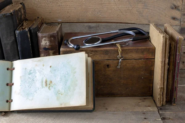 听诊器和一张旧桌子上的箱子 医学杂志和医疗用品在一张木桌上 深色背景 — 图库照片
