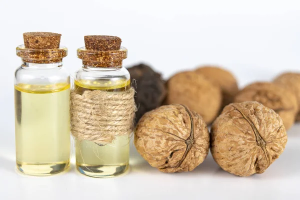 Oil in a bottle and walnuts on a white kitchen table. Spices and ingredients useful in kuchi. White background.