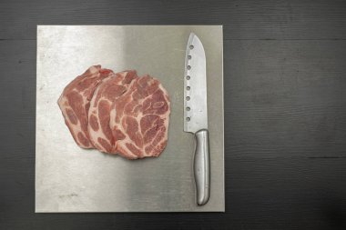 Domuz eti boyun metal masa üzerinde parçalar halinde kesin. Dörde bir mezbahada et. Siyah arka plan.