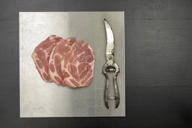 Domuz eti boyun metal masa üzerinde parçalar halinde kesin. Dörde bir mezbahada et. Siyah arka plan.