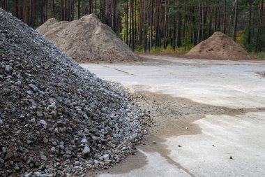 Beton bir meydanda kum yığını. Malzeme bileşimi inşaatçılar için malzeme sayısı. Sezon sonbahar.