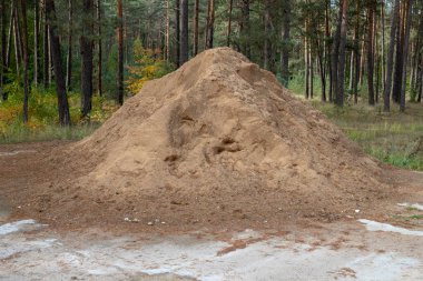 Beton bir meydanda kum yığını. Malzeme bileşimi inşaatçılar için malzeme sayısı. Sezon sonbahar.