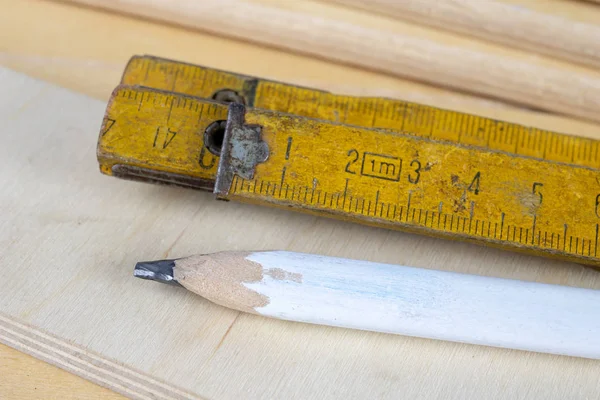 Carpenter\'s measure and pencil on a workshop table. Measurement of material in the woodworking shop. White background.