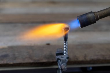 Metal gaz yakıcı bir ev atölye ile Isıtma. Çelik alevler ile temperleme. Koyu arka plan.