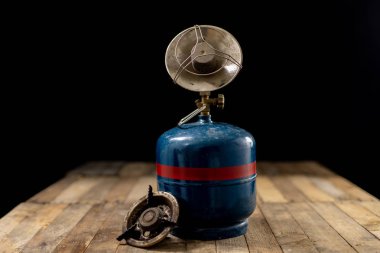 Bir eski gaz yemekleri hazırlamak için yazıcı. Eski ahşap masa turistik aksesuarlar. Koyu arka plan.