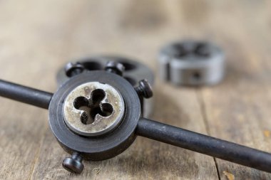 Metal işleri araçlar atölye masada. İş parçacığı ölür ve bir eski tozlu atölyede musluklar. Siyah arka plan.