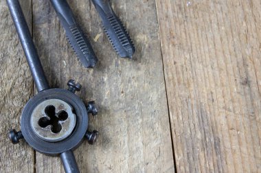 Metal işleri araçlar atölye masada. İş parçacığı ölür ve bir eski tozlu atölyede musluklar. Siyah arka plan.