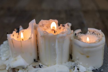 Ahşap bir masa üzerinde kirli balmumu ile eski mumlar. Kirli şamdanlar bir cam stand üzerine yazma. Koyu arka plan.