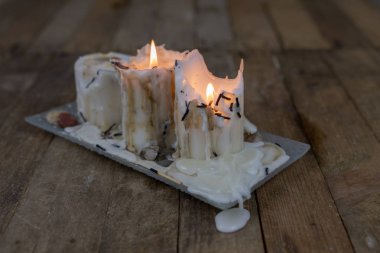 Ahşap bir masa üzerinde kirli balmumu ile eski mumlar. Kirli şamdanlar bir cam stand üzerine yazma. Koyu arka plan.