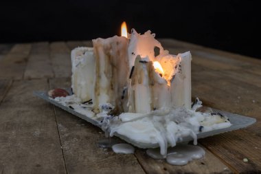 Ahşap bir masa üzerinde kirli balmumu ile eski mumlar. Kirli şamdanlar bir cam stand üzerine yazma. Koyu arka plan.