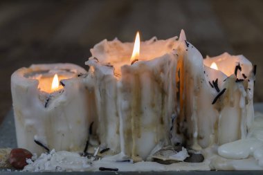 Ahşap bir masa üzerinde kirli balmumu ile eski mumlar. Kirli şamdanlar bir cam stand üzerine yazma. Koyu arka plan.