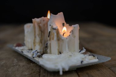 Ahşap bir masa üzerinde kirli balmumu ile eski mumlar. Kirli şamdanlar bir cam stand üzerine yazma. Koyu arka plan.