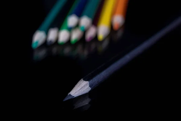 Pencils on the glass. Colored pencil pencils for coloring on the table. Dark background.