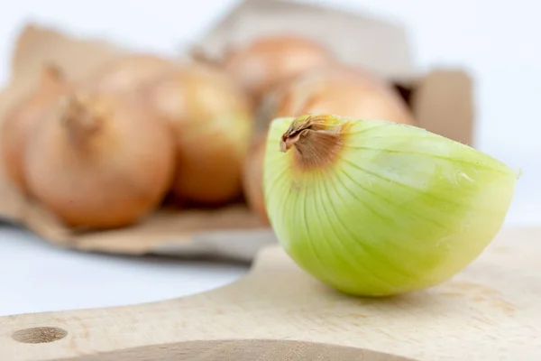 Onion in a paper bag on a white kitchen table. Vegetables for preparing dishes in the home kitchen. White background.