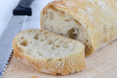 Taze ekmek ahşap mutfak tahtası. Bir dilim ekmek ve tereyağı ile bulaşmış. açık renkli.