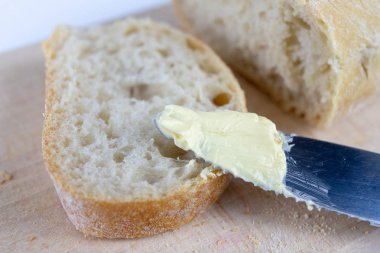 Taze ekmek ahşap mutfak tahtası. Bir dilim ekmek ve tereyağı ile bulaşmış. açık renkli.