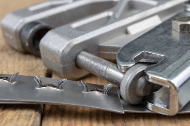 Bir crimper kullanarak bir sac bağlar. Küçük çilingir mekanik bir atölyede çalışıyor. Koyu arka plan.