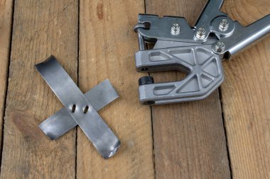 Bir crimper kullanarak bir sac bağlar. Küçük çilingir mekanik bir atölyede çalışıyor. Koyu arka plan.