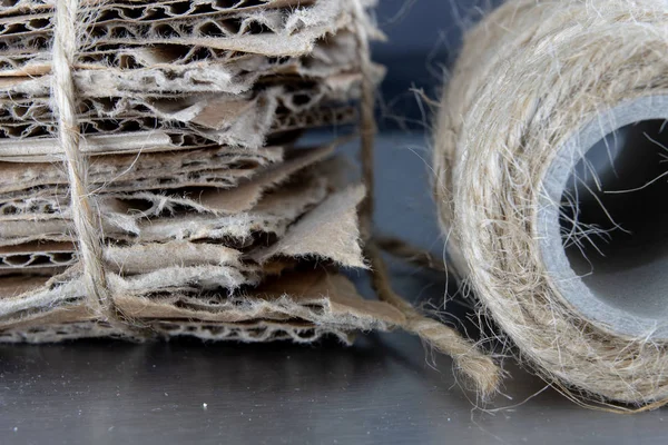 Waste paper bound with a gray cord. Old papers and cardboard intended for recycling. Dark background.