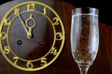 Eski bir saat ve gözlük New Year's Eve şampanya dolu. Yeni yıl için beş dakika. Koyu arka plan.