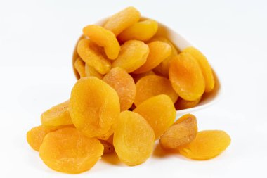 Beyaz bir kase lezzetli kuru kayısı. Mutfak masasında kek için davranır. Beyaz arka plan.