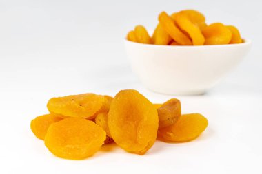 Beyaz bir kase lezzetli kuru kayısı. Mutfak masasında kek için davranır. Beyaz arka plan.