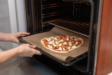 Ev bir mutfak lezzetli pizza hazırlanması. Döşeme ve dekorasyon pizza hamuru mutfak masasının üzerinde. Açık renkli.