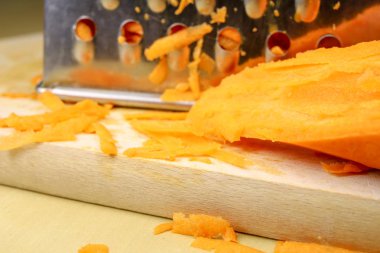 Bir metal mutfak rendeleyin taze havuç rendesi. Mutfak masasının üzerinde bir yemekle salata için hazırlanan sebzeler. Açık renkli.