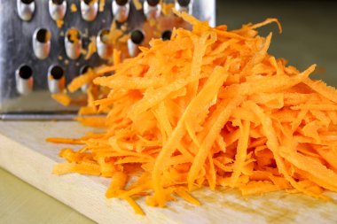 Bir metal mutfak rendeleyin taze havuç rendesi. Mutfak masasının üzerinde bir yemekle salata için hazırlanan sebzeler. Açık renkli.