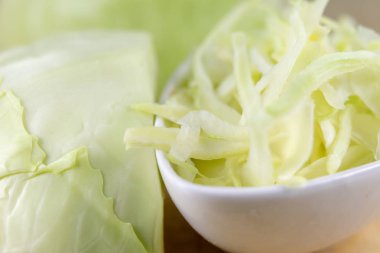 Taze beyaz lahana mutfak masasında şeritler halinde kesin. Sebze salatası için hazırlanmış. Açık renkli.