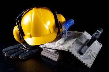 Fayans ve kask siyah bir masada döşeme için araçları. İnşaat işçileri için aksesuarlar. Koyu arka plan.