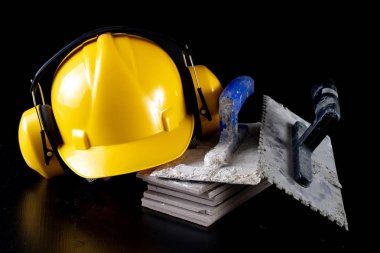 Fayans ve kask siyah bir masada döşeme için araçları. İnşaat işçileri için aksesuarlar. Koyu arka plan.