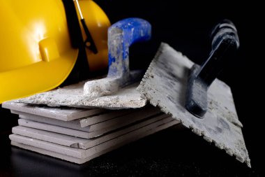 Fayans ve kask siyah bir masada döşeme için araçları. İnşaat işçileri için aksesuarlar. Koyu arka plan.