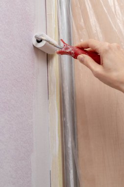 Evde duvara boya silindiri uygulanıyor. Yenileme ev koşullarında. Açık renkli.