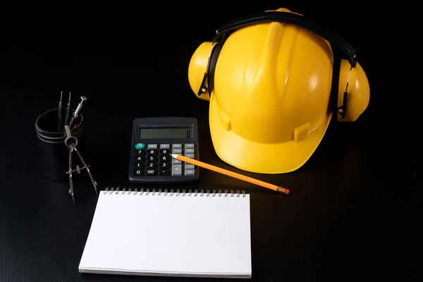 Engineer\'s desk prepared for work. Accessories prepared for a builder on a black table. Dark background.