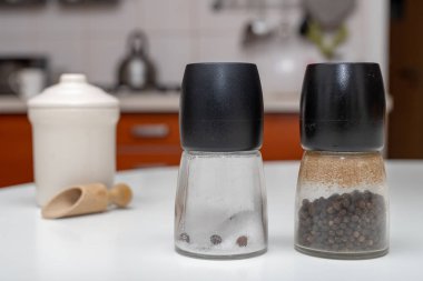 Tuz ve biber kaplarda mutfak masasının üzerinde. Ev mutfak baharat. Açık renkli.