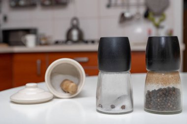 Tuz ve biber kaplarda mutfak masasının üzerinde. Ev mutfak baharat. Açık renkli.