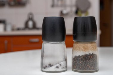 Tuz ve biber kaplarda mutfak masasının üzerinde. Ev mutfak baharat. Açık renkli.