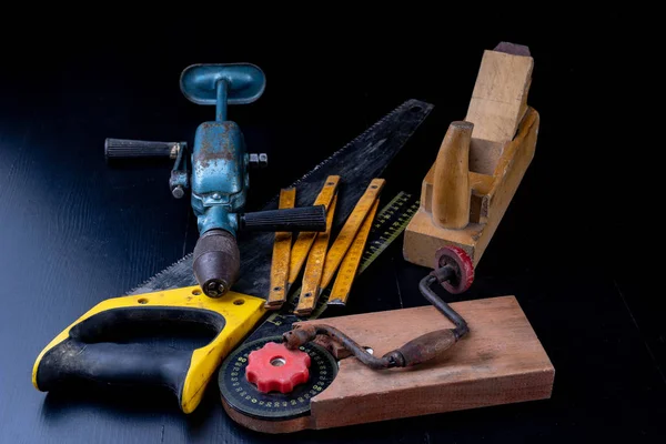 Tools for a carpenter on a workshop table. Accessories for a production worker. Dark background.