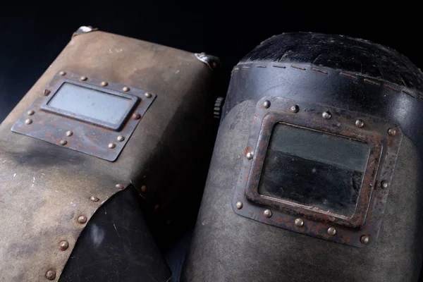 An old mask for the welder. Accessories for a production worker. Dark background.