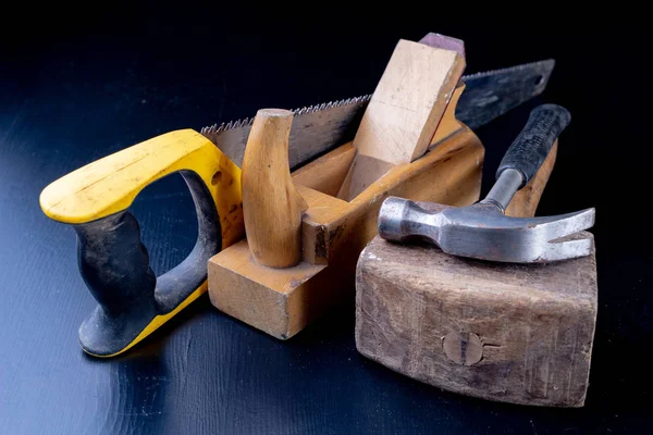 Tools for a carpenter on a workshop table. Accessories for a production worker. Dark background.