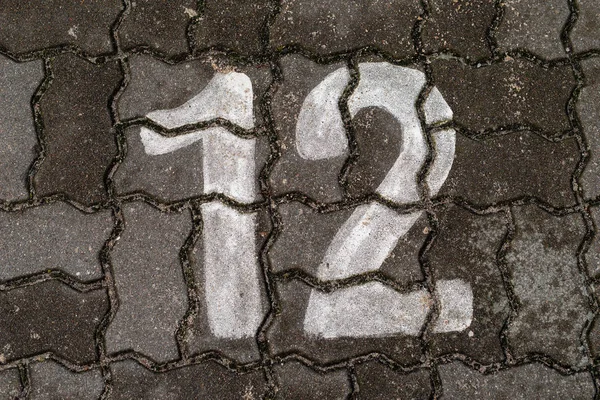 Parking space number painted on a paving stone. Parking signs for passenger cars. Season of the autumn