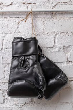 Siyah boks eldivenleri beyaz tuğla duvara asılı. Eğitim aksesuarları. Beyaz arka plan.
