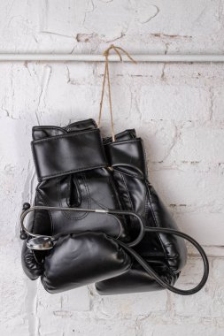 Siyah boks eldivenleri ve tıbbi bir stetoskop bir tuğla duvar. Eğitim aksesuarları. Beyaz arka plan.