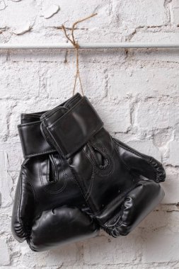 Siyah boks eldivenleri beyaz tuğla duvara asılı. Eğitim aksesuarları. Beyaz arka plan.