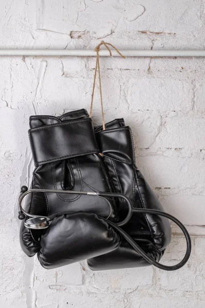 Siyah boks eldivenleri ve tıbbi bir stetoskop bir tuğla duvar. Eğitim aksesuarları. Beyaz arka plan.