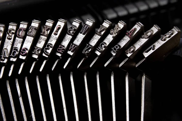 Font in a typewriter. Metal stamps for imprinting letters on a white sheet. Light background.