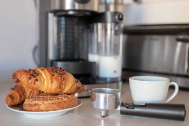 Taze yapılmış kahve kahve makinesi ve lezzetli tatlı çörek. Ev mutfakta kahvaltı. Açık renkli.