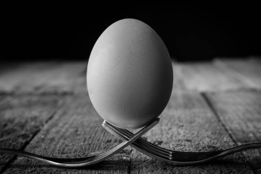 Yumurta çatal üzerinde düzenlenmiştir. Ahşap masa. Koyu arka plan.