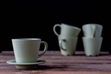 Kahve bardağı ahşap bir masa üzerinde. Siyah arka plan.